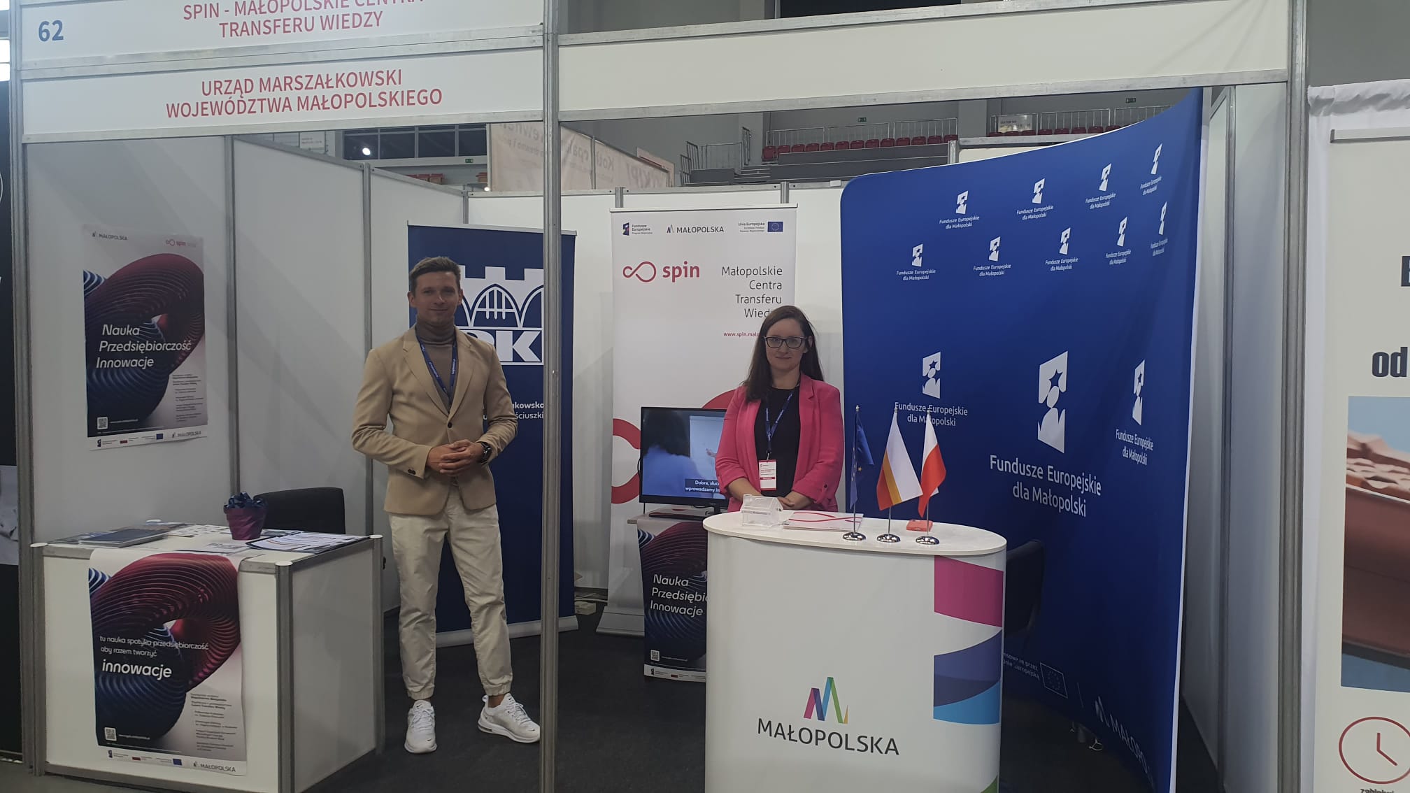 Zdjęcie przedstawia 2 osoby na stoisku wystawienniczym projektu SPIN podczas targów