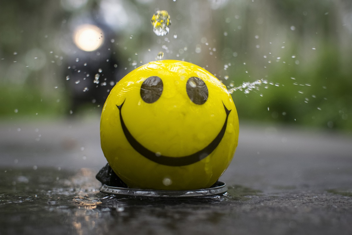 Uśmiechnięta żółta piłka na deszczu